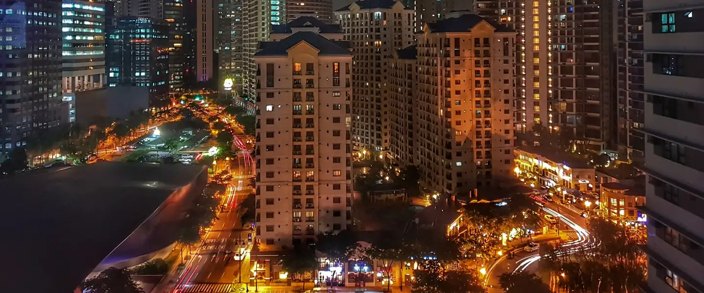 A vibrant nighttime view of Bonifacio Global City featuring luxury residential towers and walkable green spaces in Taguig.