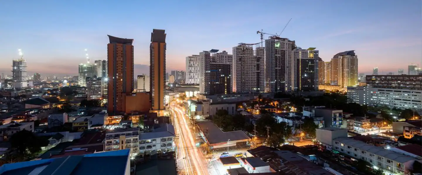 An aerial view of Quezon City's expansive urban landscape, showcasing dense city developments, modern commercial towers, and major road networks.